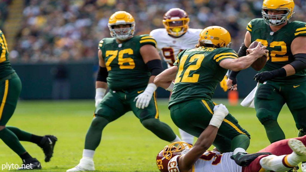 Close-up of Aaron Rodgers on the sidelines, encouraging teammates during a game.