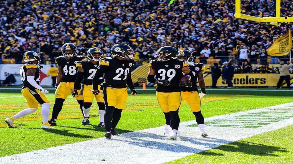 Russell Wilson in a huddle with Pittsburgh Steelers teammates on the field.